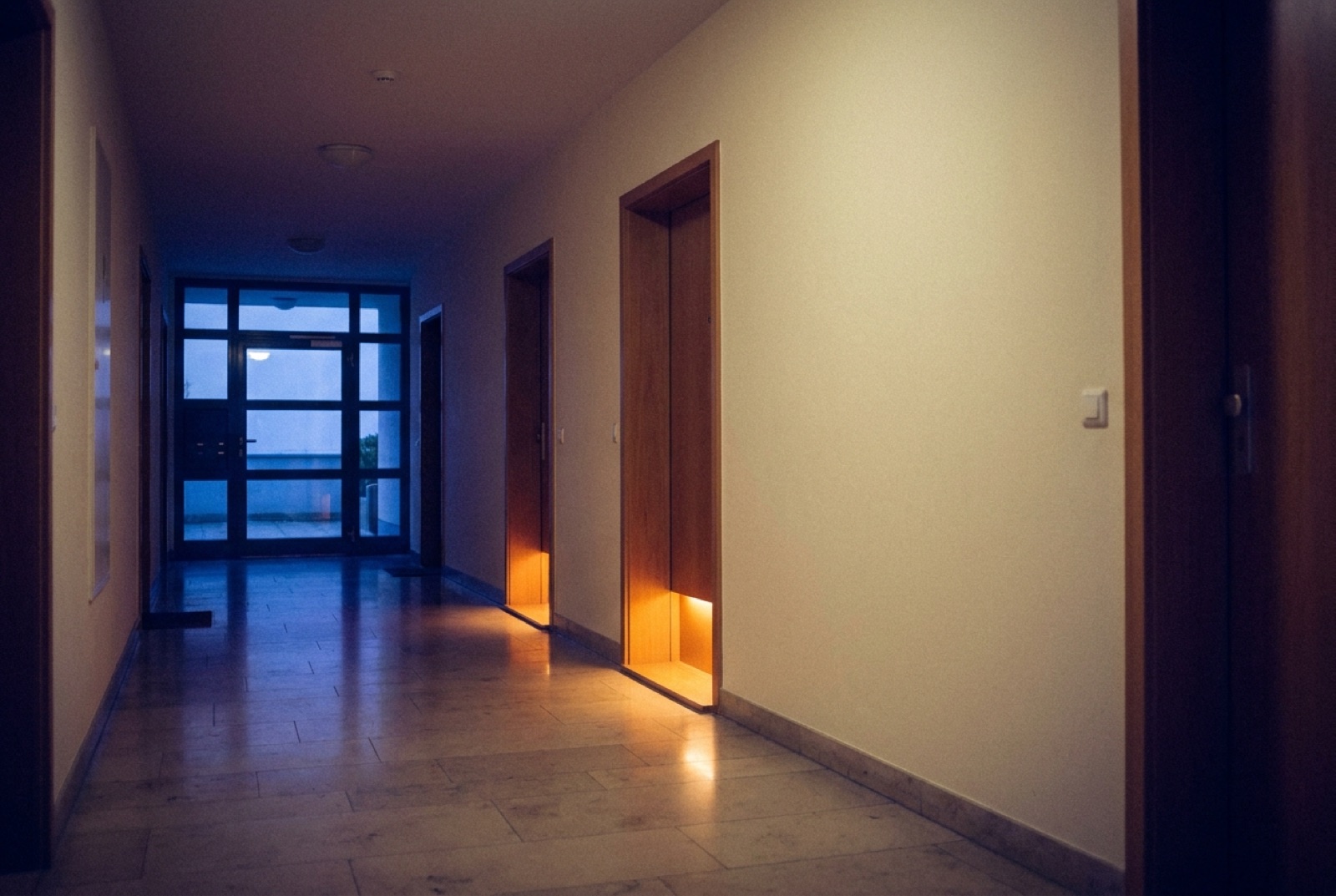 Hausflur nach Feierabend, unter zwei Wohnungstüren brennt noch Licht