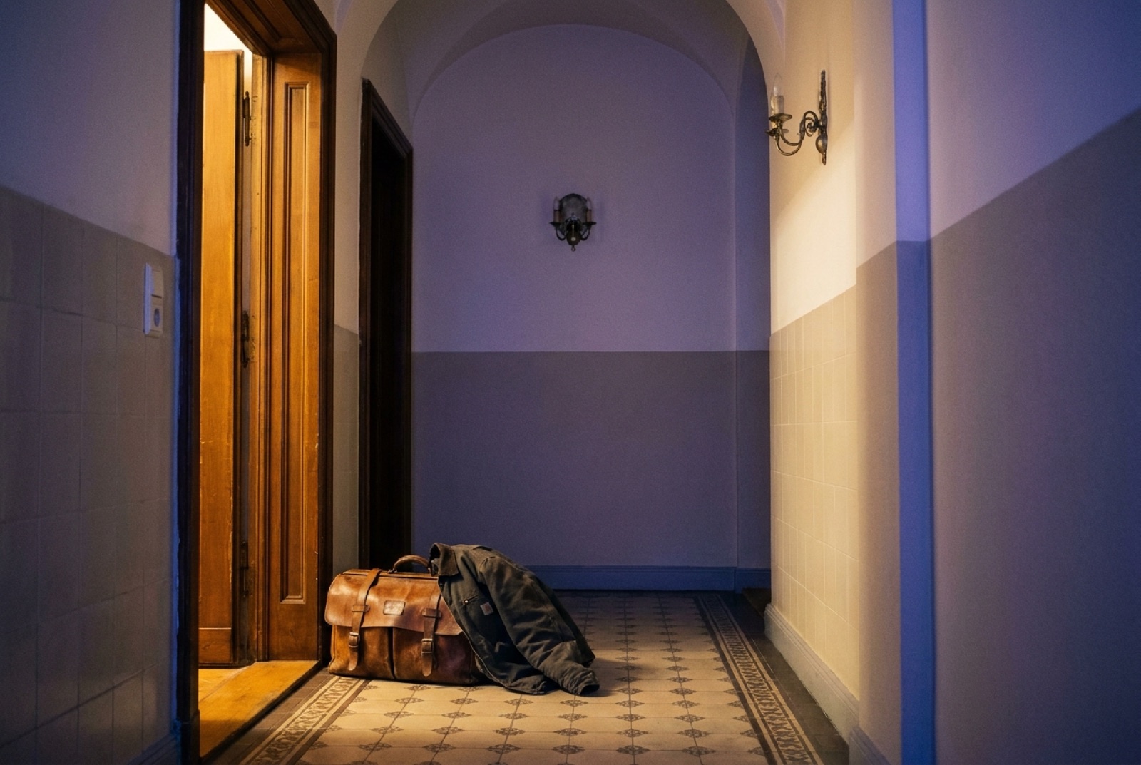Werkzeugtasche und Arbeitsjacke vor einer offenen Wohnungstür im Altbauflur, warmes Licht aus der Wohnung
