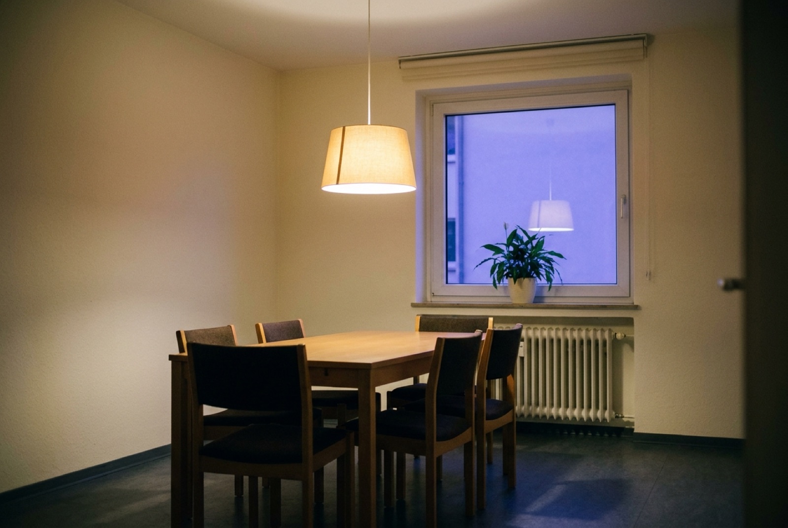 Gemeinschaftsraum nach der Eigentümerversammlung, die Lampe brennt noch über dem leeren Tisch